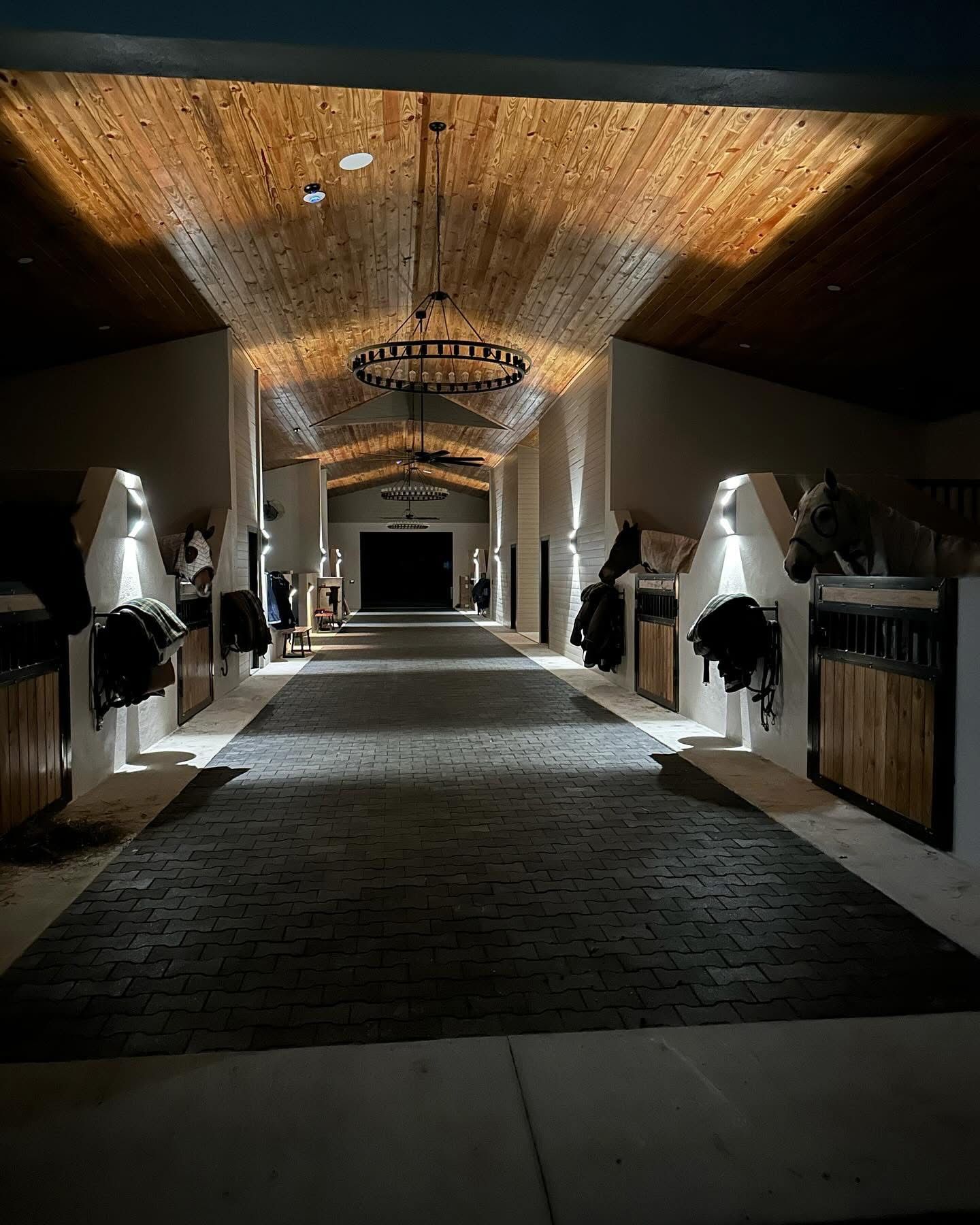 Barn aisle at night with timber ceiling and wall sconces